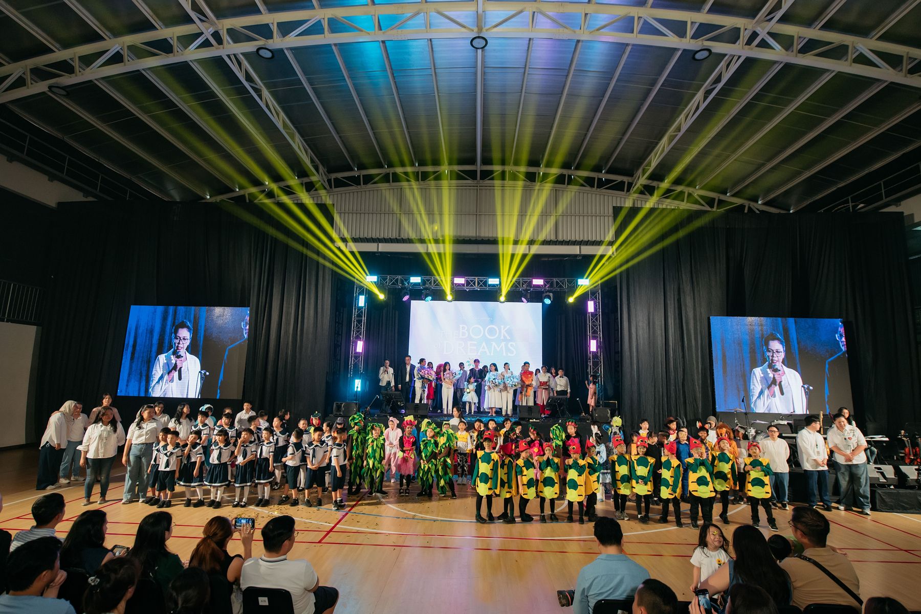 Students on stage under coloured lights at a school event in the hall