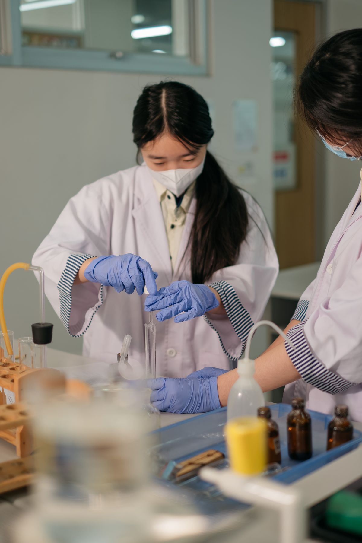 A student in a lab coat measuring liquid in the science lab
